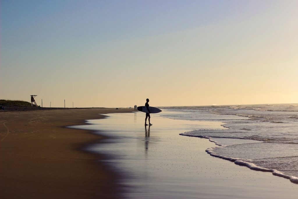 A foto retrata um surfista entrando no mar em Florianópolis, uma das Melhores Cidades do Brasil para Nomades Digitais