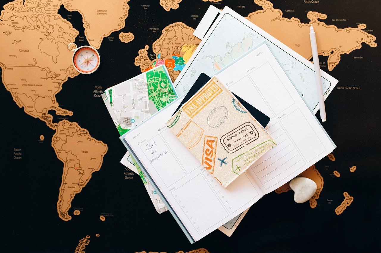 A imagem mostra documentos de migração e um passaporte carimbado, representando o processo de visto para nômades digitais.